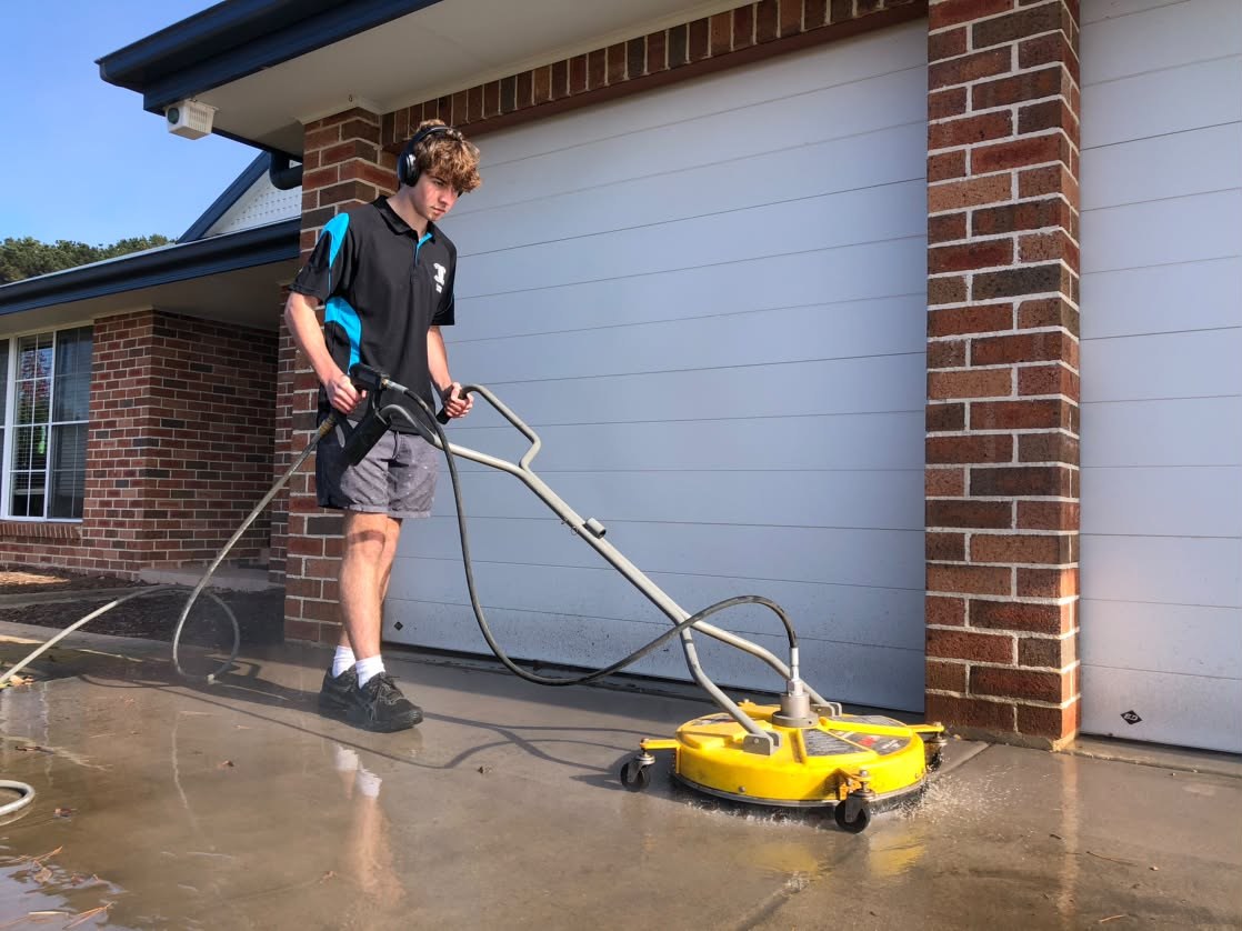 Technician using a commercial surface cleaner on a Canberra driveway