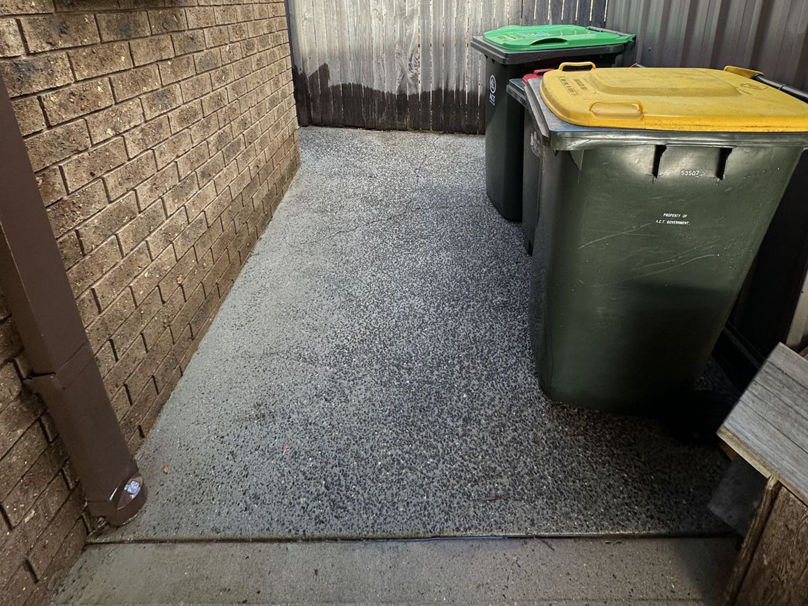 The same concrete bin area and home surrounds after pressure washing and chemical treatment