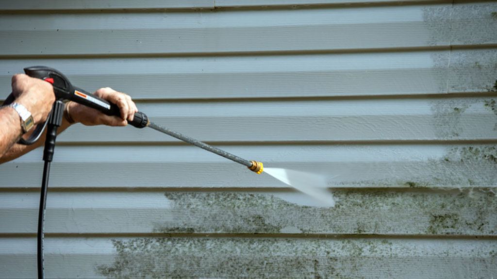 Low-pressure soft wash removing mildew and algae from house cladding